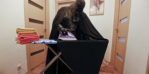 Ein Mann im Darth-Vader-Kostüm bügelt