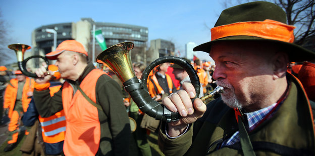Jäger bei einer Demonstration in Düsseldorf mit orangen Warnwesten und Jagdhörnern