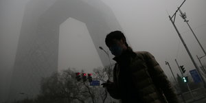 Ein Mann steht auf der Straße, der Smog verdeckt die Sicht.