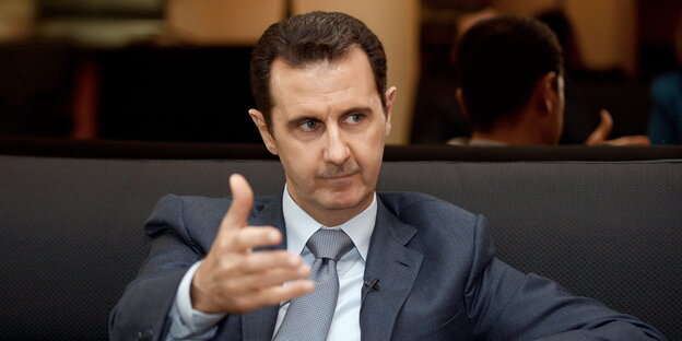 Assad hält die Hand in die Kamera