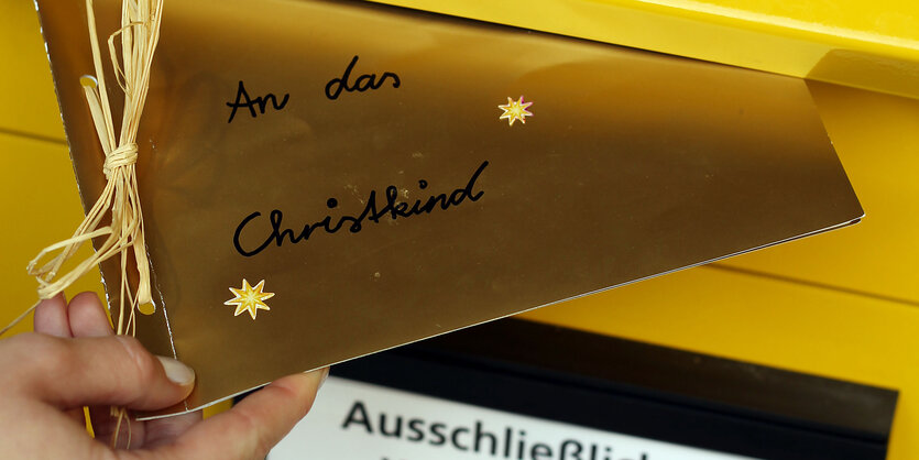 Eine Frau wirft einen Brief ans Christkind in den Postkasten.