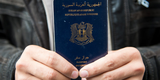 Hände halten einen syischen Pass