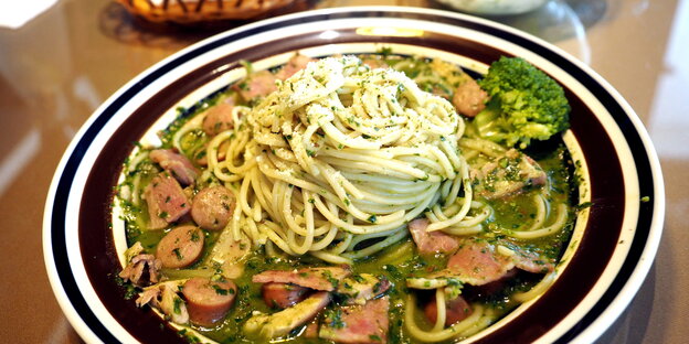 Ein Teller Spaghetti mit Würstel und Brokkoli