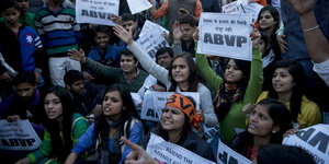 Junge Frauen und Männer protestieren in Indien mit Plakaten