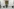 Wahlkabine in einem Wahllokal, eine Person mit dunkler Hose und schwarzen Schuhe sitzt hinter dem Sichtschutz - auf dem Boden ein schwarzer Mülleimer - links und rechts sind Wahlkabinen im Anschnitt zu erkennen