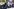 Studentinnen nehmen an der Demonstration gegen Kürzungen teil, zu sehen sind ihre Gesichter und die Hände, die ein Banner tragen oder eine Fahne hochhalten. Sie haben ernste Gesichter, eine junge Frau mit lila Haaren hat kleine Sterne im Gesicht