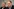 Ein Mann in Jackett und hellem Hemd spricht und blickt nach rechts, im Hintergrund ist ein zweiter Mann leicht unscharf zu sehen.