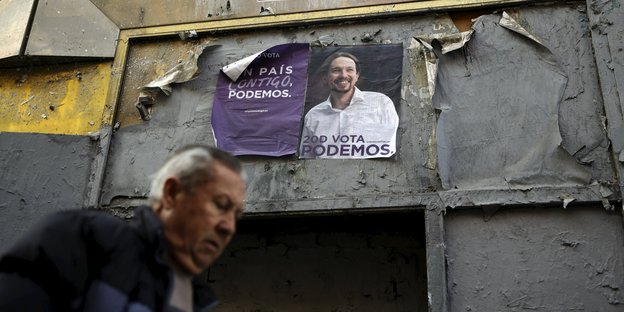 Podemos-Plakat an einer Häuserwand, davor ein Mann