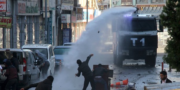 Protestierende und ein Wasserwerfer auf einer Straße