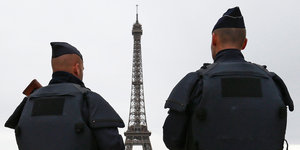 Zwei französische Polizisten patroullieren vor dem Eiffelturm.