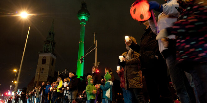 Teilnehmer einer Lichterkette stehen am 17.10.2015 in Berlin am Alexanderplatz.