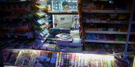 Ein Verkäufer liest in Berlin-Friedenau in seinem Kiosk in einer Zeitung.
