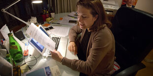 Frau Gauthier am Schreibtisch mit einem Blatt Papier in der Hand.