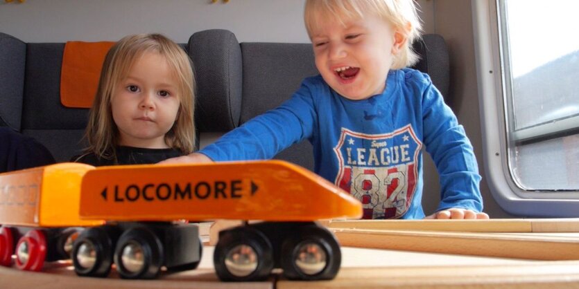 Kinder spielen mit einer Holzbahn