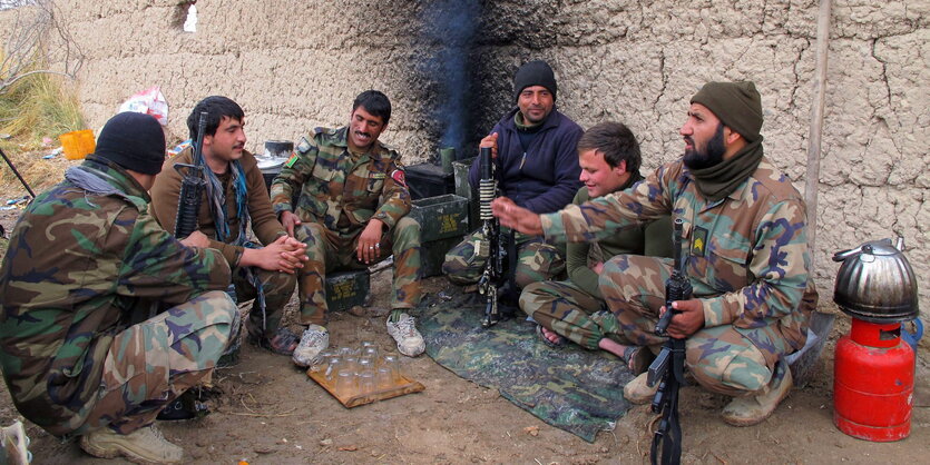 Soldaten sitzen vor einer Mauer