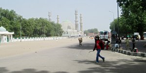 Ein Mensch läuft über eine leere Straße, im Hintergrund die Türme einer Moschee