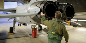 Ein Waffensystemoffizier in Tarnfarben legt Hand an eine Flugzeugturbine