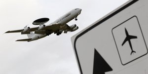 Ein Awacs-Aufklärer fliegt an einem Flughafenschild vorbei