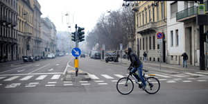 Vermummter Radfahrer fährt über leere Kreuzung