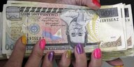 Hände mit bunt lackierten Fingernägeln halten Geldscheine