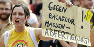 Junge Frau mit Schild, auf dem steht "Gegen Bachelor-Massenabfertigung!"