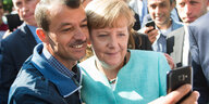 Ein Asylsuchender macht ein Selfie mit Angela Merkel