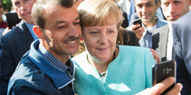 Ein Asylsuchender macht ein Selfie mit Angela Merkel