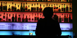 Mensch sitzt an einer buntbeleuchteten Bar