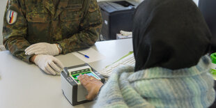 Eine Frau ist von hinten zu sehen, ihre Hand liegt auf einem Fingerabdruckscanner