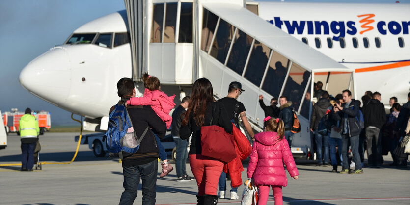 Menschen laufen auf einem Rollfeld auf ein Flugzeug zu