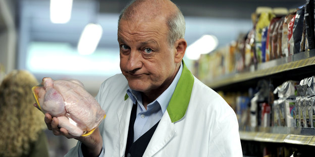 Ein Mann hält ein für den Verkauf verpacktes Hähnchen in der Hand