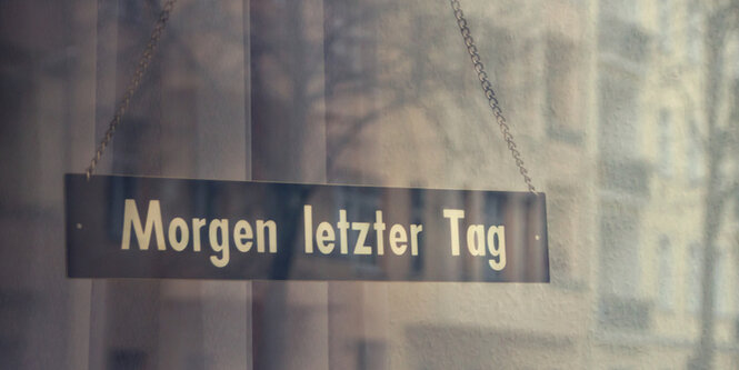 Ein Schild mit der Aufschrift „Morgen letzter Tag“ hängt in einer Tür