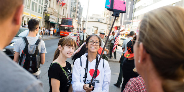Zwei Mädchen machen ein Selfie am Checkpoint Charlie.