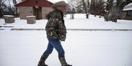 Ein Mann mit Cowboyhut und Cowboystiefeln läuft durch den Schnee