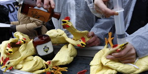 Hühner aus Gummi, die von Aktivisten symbolisch mit Gift gefüttert werden