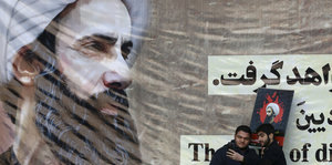 Zwei Männer vor einem Poster von Nimr al-Nimr