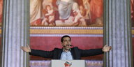 Tsipras mit ausgebreiteten Armen zwischen zwei Säulen