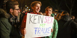 drei junge Männer mit einem Pappschild: „Kein Sex mit Frauke. Mainz bleibt bunt!!“