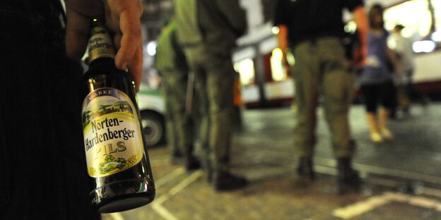 Ein Mann hält eine Bierflasche in der Hand.