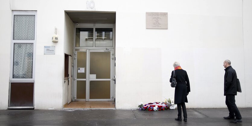 Zwei Menschen stehen vor Blumen vor einem Gebäude