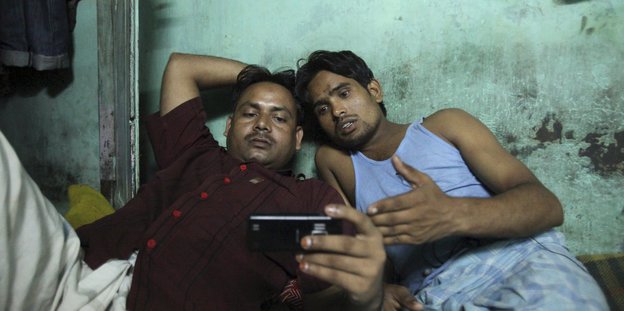 Zwei Männer schauen im Liegen auf ein Smartphone