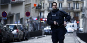 Ein Polizist in Schutzkleidung mit gezogener Pistole in Paris