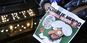Eine Frau hält eine Ausgabe von Charlie Hebdo