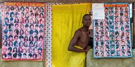 Ein junger Mann schaut aus einem Friseursalon in Angola.