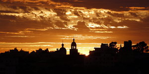 Die schwarze Siluette von Hebron, dahinter gold-braunes Licht der untergehenden Sonne