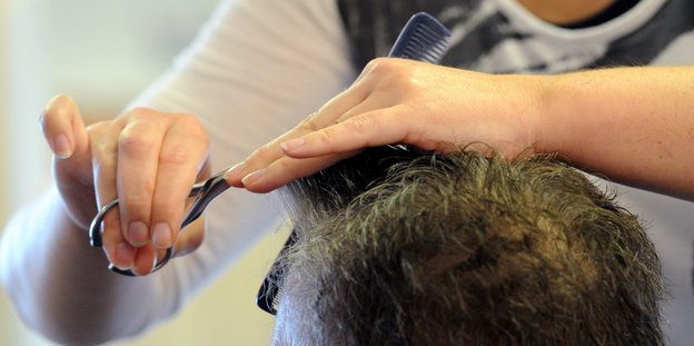Ein Friseur schneidet einem Kunden die Haare.
