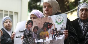 Vier Frauen halten auf einer Demonstration in Beirut ein Schild gegen die Belagerung Madayas hoch, auf dem in arabischer Sprache steht "Rettet Madayas Kinder"