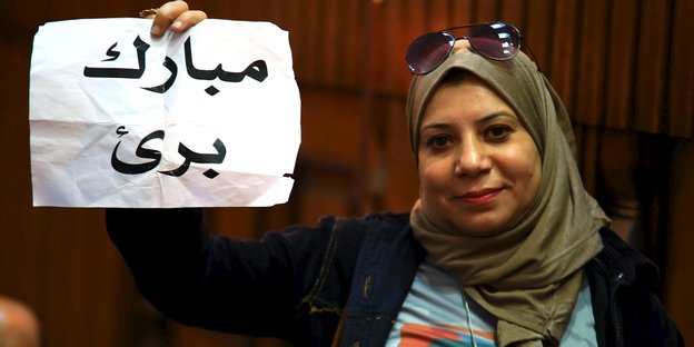 Eine Frau hält einen Zettel hoch, auf dem in arabischer Schrift steht: Mubarak ist unschuldig.
