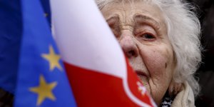 Eine ältere Frau hinter einer polnischen Flagge und einer EU-Flagge