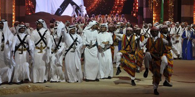 Männer in traditioneller saudischer Tracht auf einer Bühne.